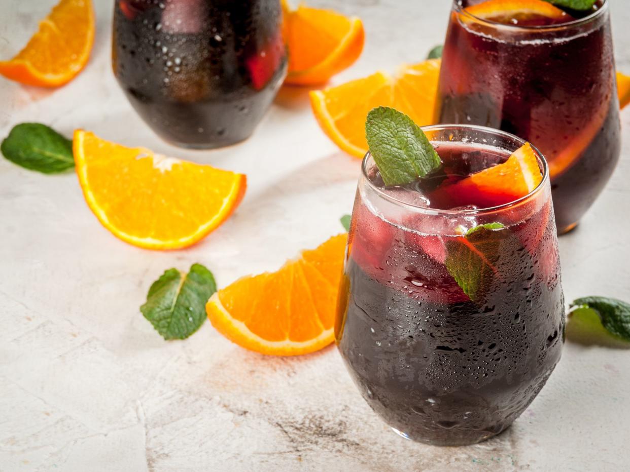 Traditional Spanish summer refreshing drink, cocktail, Tinto de verano. With wine, ice and pieces of fresh orange. On white stone table, copy space