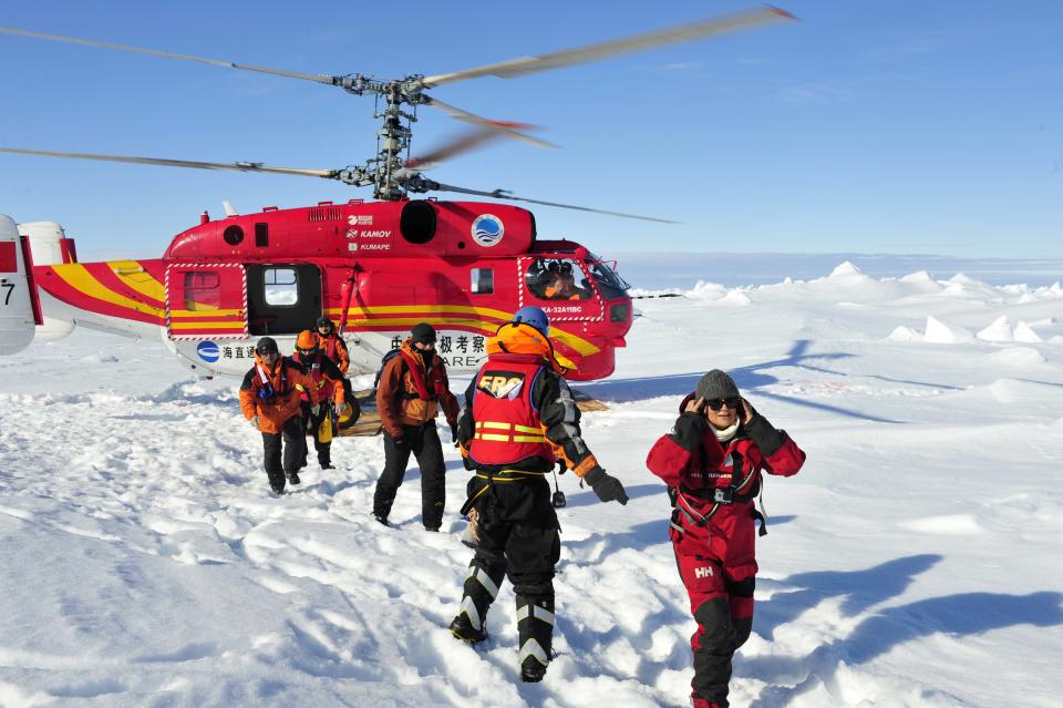 In this photo provided by China's Xinhua News Agency, the first group of passengers who were aboard the trapped Russian vessel MV Akademik Shokalskiy arrive at a safe surface off the Antarctic, Thursday, Jan. 2, 2014. The helicopter rescued all 52 passengers from the research ship that has been trapped in Antarctic ice, 1,500 nautical miles south of Hobart, Australia, since Christmas Eve after weather conditions finally cleared enough for the operation Thursday. (AP Photo/Xinhua, Zhang Jiansong) NO SALES