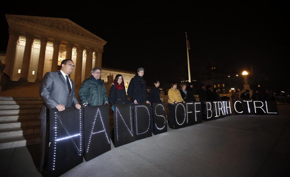 A group of people organized by the NYC Light Brigade and the women's rights group UltraViolet, use letters in lights to spell out their opinion, in front of the Supreme Court, Monday, March 24, 2014 in Washington. Holding the "H" in "Hands" at left, is Rep. Keith Ellison, D-Minn. The Supreme Court is weighing whether corporations have religious rights that exempt them from part of the new health care law that requires coverage of birth control for employees at no extra charge. (AP Photo/Alex Brandon)