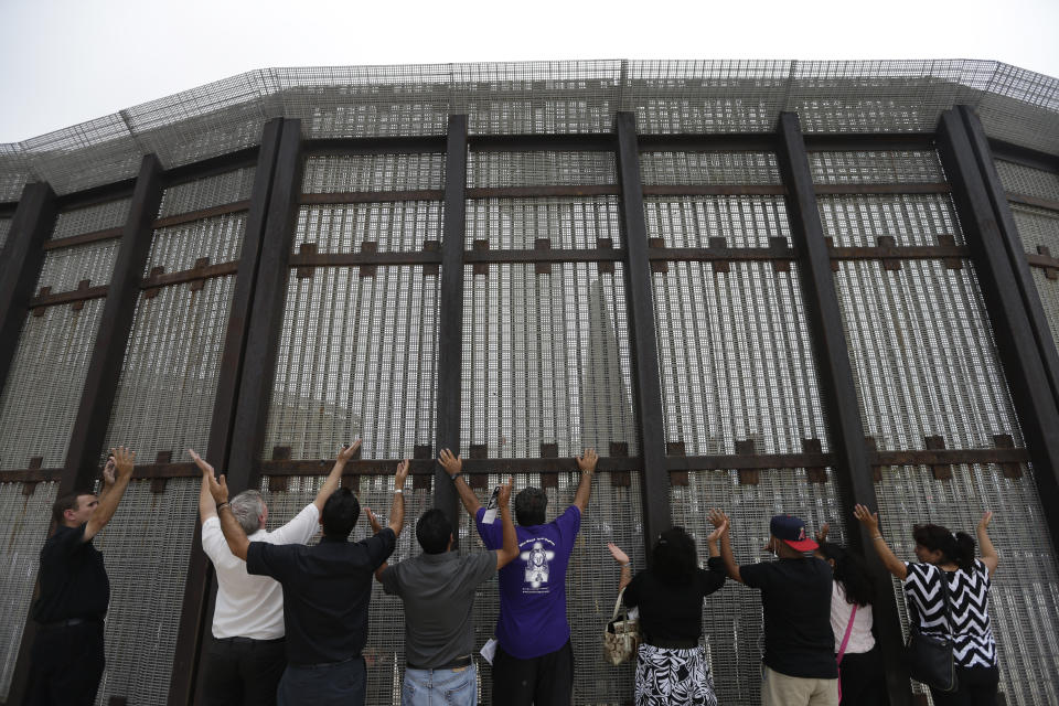 FILE - In this July 14, 2013, file photo, pastors and others raise their arms on the San Diego side of a border fence during a cross-border Sunday religious service with others on the Tijuana, Mexico side of the fence. The Tijuana and San Diego border crossing is the world's busiest land border crossing, but also now sees relatively few illegal crossings. (AP Photo/ Gregory Bull, File)