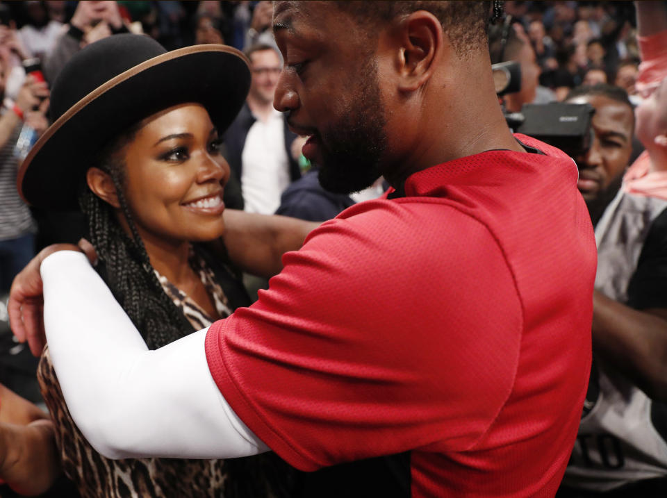 Miami Heat guard Dwyane Wade, left, has a few words with his wife, Gabrielle Union, before the team's BA basketball game against the Brooklyn Nets, Wednesday, April 10, 2019, in New York, Wade's final NBA game. (AP Photo/Kathy Willens)