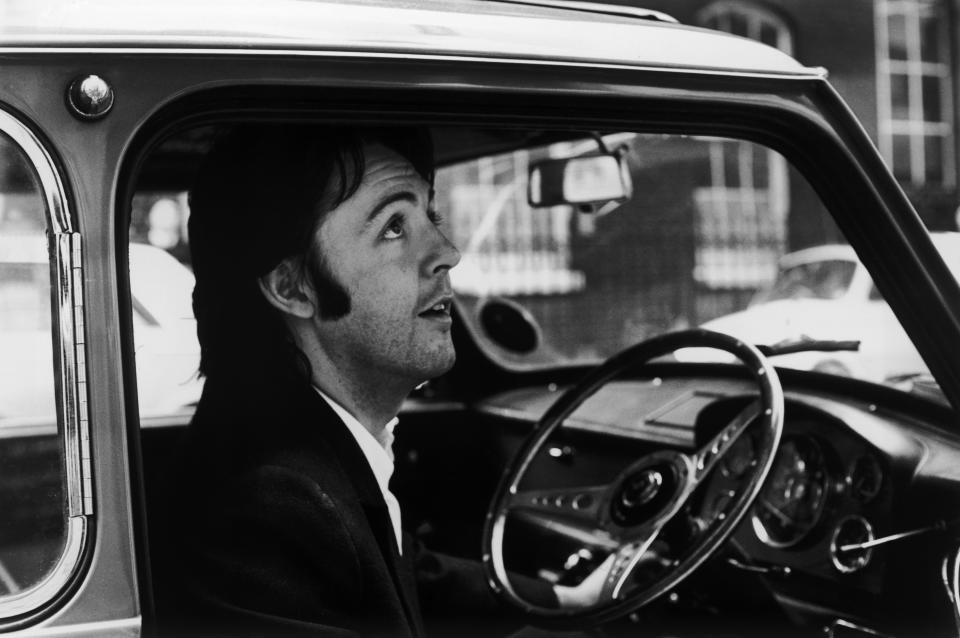 Paul McCartney sits at the steering wheel of a car. 