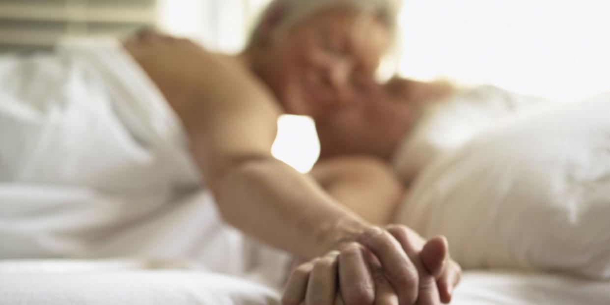 senior couple holding hands in bed