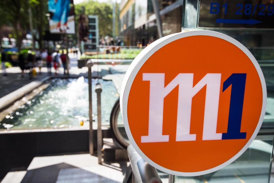 Signage for MobileOne Ltd. (M1) stands near an escalator in Singapore, on Monday, Feb. 29, 2016. PHOTO: Nicky Loh/Bloomberg