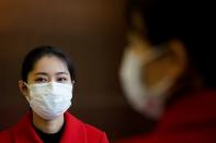 Staff members wearing face masks are seen at an entrance of a shopping mall in Wuhan