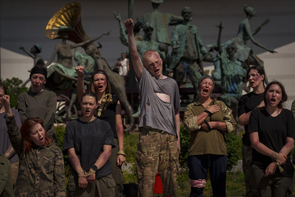 Ukrainian refugees, playing roles of Ukrainian war prisoners, sing their country's national anthem at the end of an event in Bucharest, Romania, Saturday, April 13, 2024. Members of the Ukrainian refugee community staged an event dubbed "Voices of Captives" to raise awareness to the plight of Ukrainian servicemen and civilians still in Russian custody. (AP Photo/Vadim Ghirda)