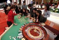 Casino dealer trainees practise on a roulette table inside Solaire Casino in Pasay city, Metro Manila, Philippines, March 27, 2015. The Philippines has emerged as one of Asia's hottest gambling hubs after it launched its 120-hectare (1.2 square km) gaming and leisure enclave called Entertainment City in the capital, modelled on the Las Vegas strip. When paying your final respects for a relative or friend, the last thing you might expect to see at the wake is people placing bets on a card game or bingo. Not in the Philippines. Filipinos, like many Asians, love their gambling. But making wagers on games such as "sakla", the local version of Spanish tarot cards, is particularly common at wakes because the family of the deceased gets a share of the winnings to help cover funeral expenses. Authorities have sought to regulate betting but illegal games persist, with men and women, rich and poor, betting on anything from cockfighting to the Basque hard-rubber ball game of jai-alai, basketball to spider races. Many told Reuters photographer Erik De Castro that gambling is only an entertaining diversion in a country where two-fifths of the population live on $2 a day. But he found that some gamble every day. Casino security personnel told of customers begging to be banned from the premises, while a financier who lends gamblers money at high interest described the dozens of vehicles and wads of land titles given as collateral by those hoping lady luck would bring them riches. REUTERS/Erik De Castro PICTURE 12 OF 29 FOR WIDER IMAGE STORY "HIGH STAKES IN MANILA". SEARCH "BINGO ERIK" FOR ALL IMAGES.