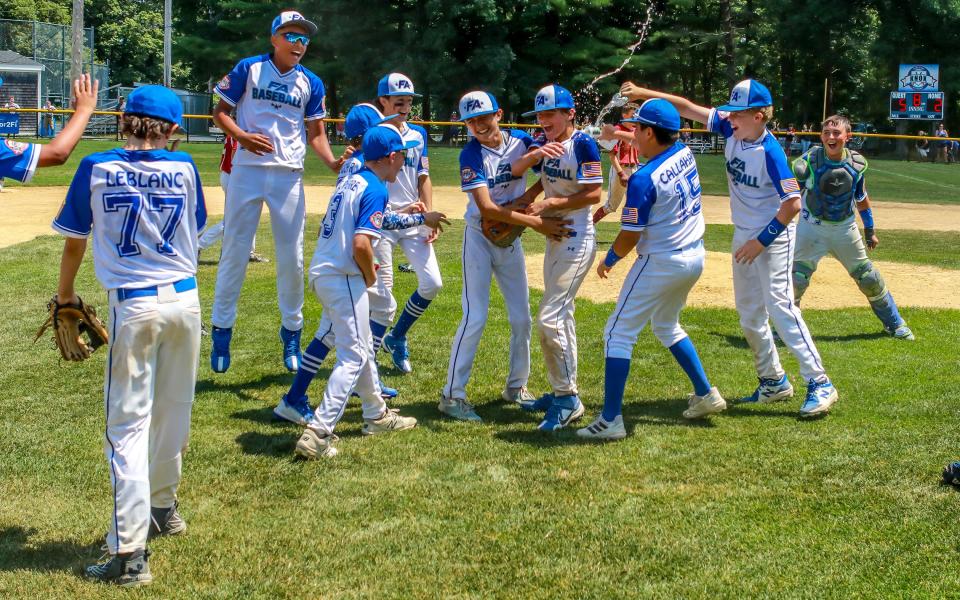 Jackson Williams is doused with water by teammates Crosby Callahan and Riley Medeiros after the final out of Fairhaven Acushnet's state championship win against Arlington, Ma. Williams picked up the win in relief of starting pitcher Gavin Bourgeois.