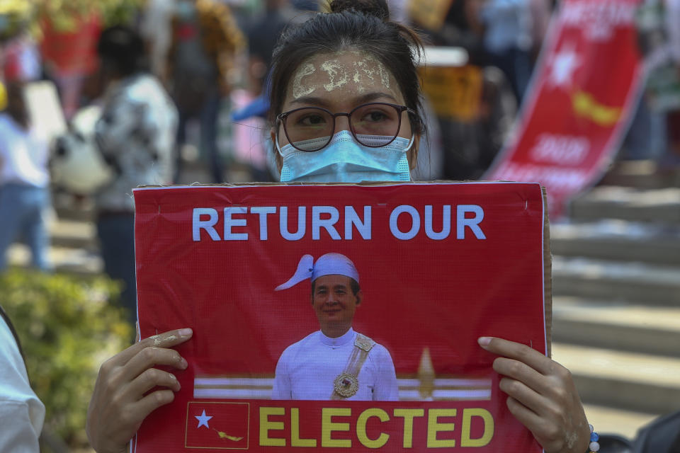 An anti-coup protester with thanaka, a traditional face paste with letters CDM, representing "Civil Disobedience Movement," displays a placard with an image of deposed Myanmar President Win Myint during a street march in Mandalay, Myanmar, Thursday, Feb. 25, 2021. Social media giant Facebook announced Thursday it was banning all accounts linked to Myanmar's military as well as ads from military-controlled companies in the wake of the army's seizure of power on Feb. 1. (AP Photo)
