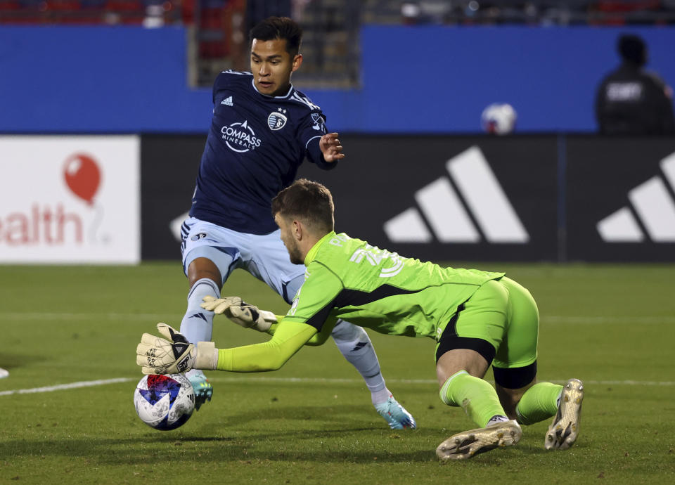 Sporting Kansas City midfielder Felipe Hernández (21) tries to score against Dallas goalkeeper Maarten Paes (30) in the second half of an MLS soccer match, Saturday, March 18, 2023, in Frisco, Texas. (AP Photo/Richard W. Rodriguez)