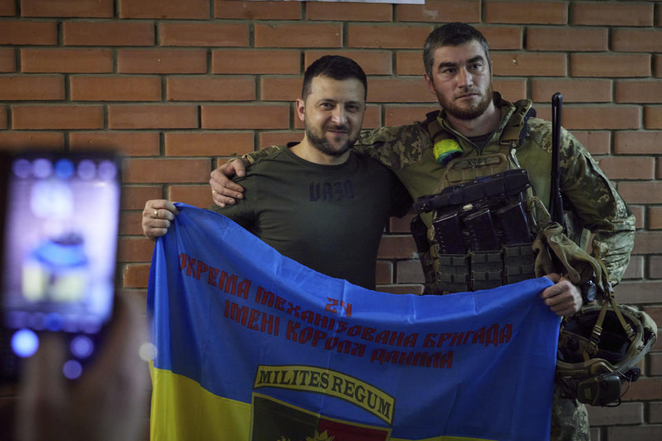 In this photo provided by the Ukrainian Presidential Press Office, Ukrainian President Volodymyr Zelenskyy, left, poses for a photo with serviceman close to the front line in Donetsk region, Ukraine, Sunday, June 5, 2022. (Ukrainian Presidential Press Office via AP)