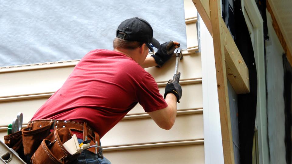 Young homeowner installs siding to his home.