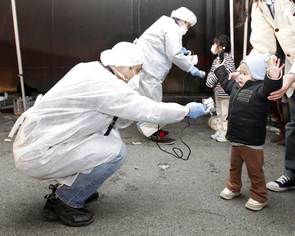 Officials in protective gear check for signs of radiation on children who are from the evacuation area near the Fukushima Daini nuclear plant in Koriyama in this March 13, 2011 photo. Reuters/Kim Kyung-Hoon/Files