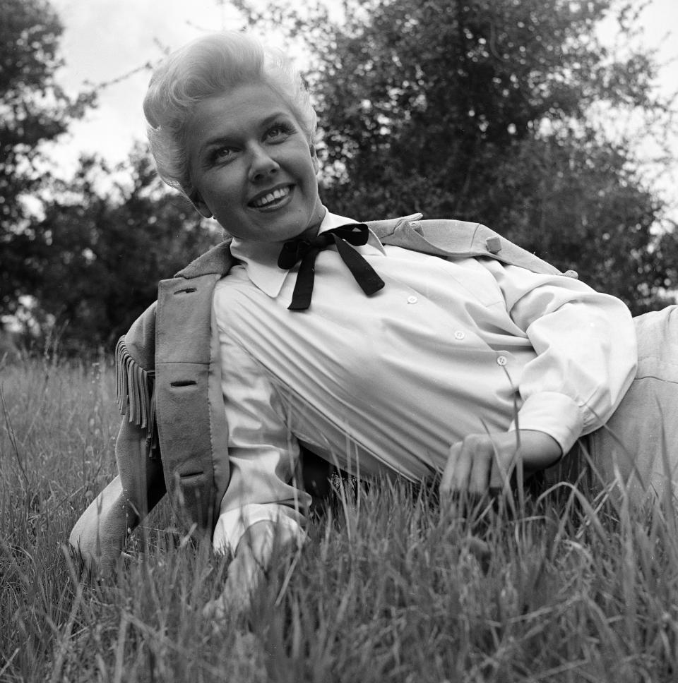 American actress and singer Doris Day lies on the grass, propped up on one elbow, in a white blouse with a buckskin coat over her shoulders, a photo shoot to publicize the musical film 'Calamity Jane' directed by David Butler, 1953. (Photo by Ed Clark/The LIFE Picture Collection via Getty Images)