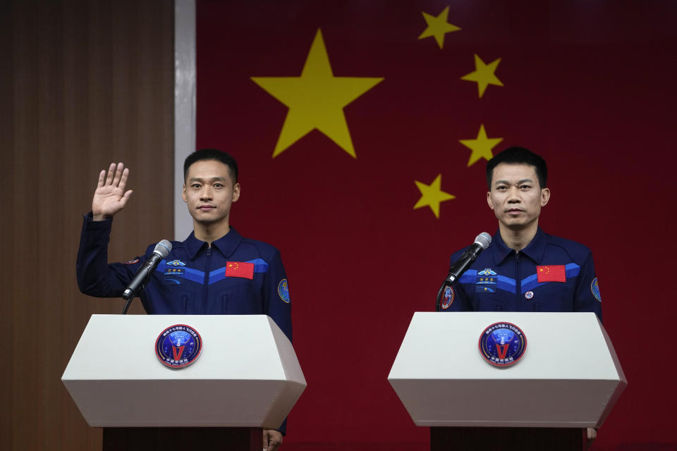 Jiang Xinlin, a Chinese astronaut for the upcoming Shenzhou-17 mission, left, waves next to his mission commander Tang Hongbo during a meeting with the press at the Jiuquan Satellite Launch Center in northwest China, Wednesday, Oct. 25, 2023. (AP Photo/Andy Wong)