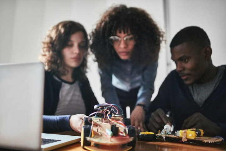 Team of engineers working on a new mechanical model. Multi-ethnic group of young people building an new technology in office.