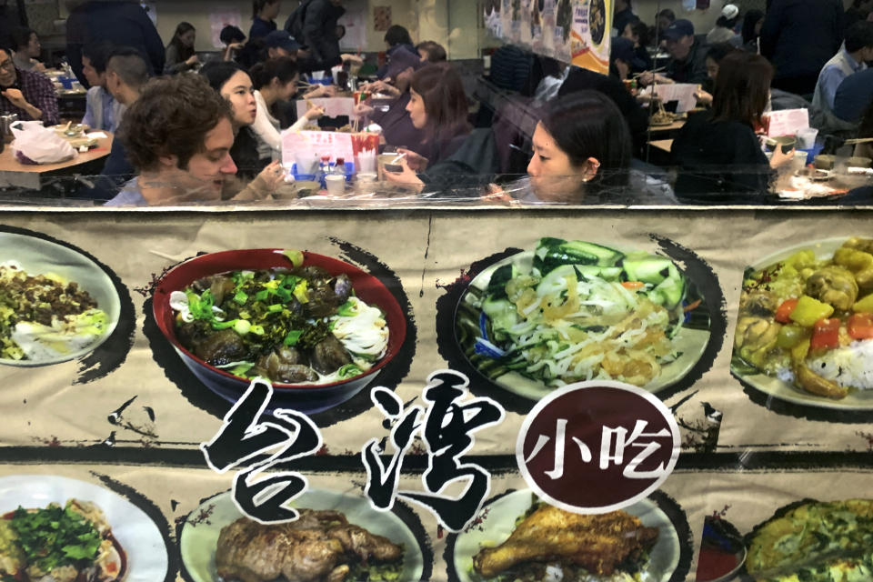 People are seen in the window eating at a Chinese restaurant decorated with menu items on its shop front on Friday Jan. 10, 2020, in New York City. A social media campaign backed by a Japanese seasonings company is targeting the persistent idea that Chinese food is packed with MSG and can make you sick. So entrenched is the notion in American culture, it shows up in the dictionary: Merriam-Webster.com lists “Chinese restaurant syndrome." as a real illness. But much of the mythology around the idea has been debunked: monosodium glutamate, also known as MSG, shows up in many foods from tomatoes to breast milk, and there's no evidence to link it to illness. (AP Photo/Wong Maye-E)