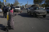 A woman kneels on the ground in front of passing Ukrainian Army car in Kherson, Ukraine, Tuesday, Nov. 15, 2022. Waves of Russian airstrikes rocked Ukraine on Tuesday, with authorities immediately announcing emergency blackouts after attacks from east to west on energy and other facilities knocked out power and, in the capital, struck residential buildings. (AP Photo/Efrem Lukatsky)