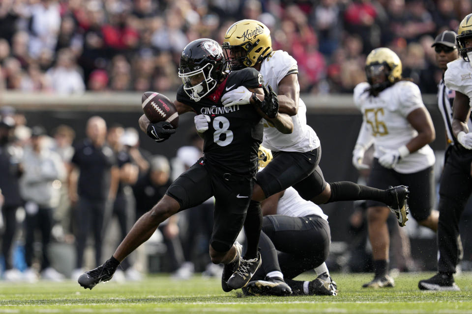 Central Florida defensive back William Wells, center right, forces a fumble against Cincinnati wide receiver Xzavier Henderson (8) during the first half of an NCAA college football game, Saturday, Nov. 4, 2023, in Cincinnati. (AP Photo/Jeff Dean)