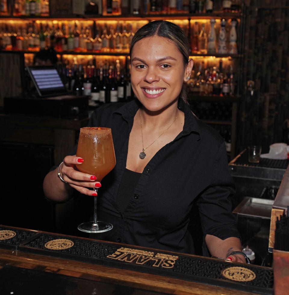 Your professional bartender who created the drinks featured in this story is Angelica Santos, who is holding another delicious drink called Harvest Sangria, made with white wine, fireball, and apple cider. Available at Barrels & Boards restaurant in Raynham, shown Thursday, Dec. 28., 2023.