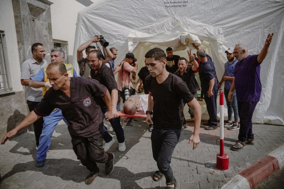 People carry a deceased body, killed in an airstrike, outside Al-Shifa Hospital, on Oct. 9.<span class="copyright">Saher Alghorra—Middle East Images/AFP/Getty Images</span>