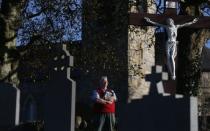 Oliver McVeigh holds a picture of his brother Columba, at their mother Vera's graveside, in Donaghmore, County Tyrone November 7, 2014. REUTERS/Cathal McNaughton