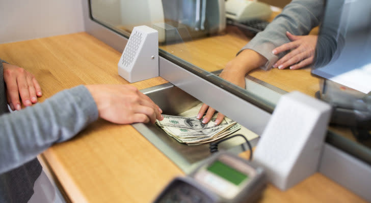 bank customer sliding money to teller at bank desk