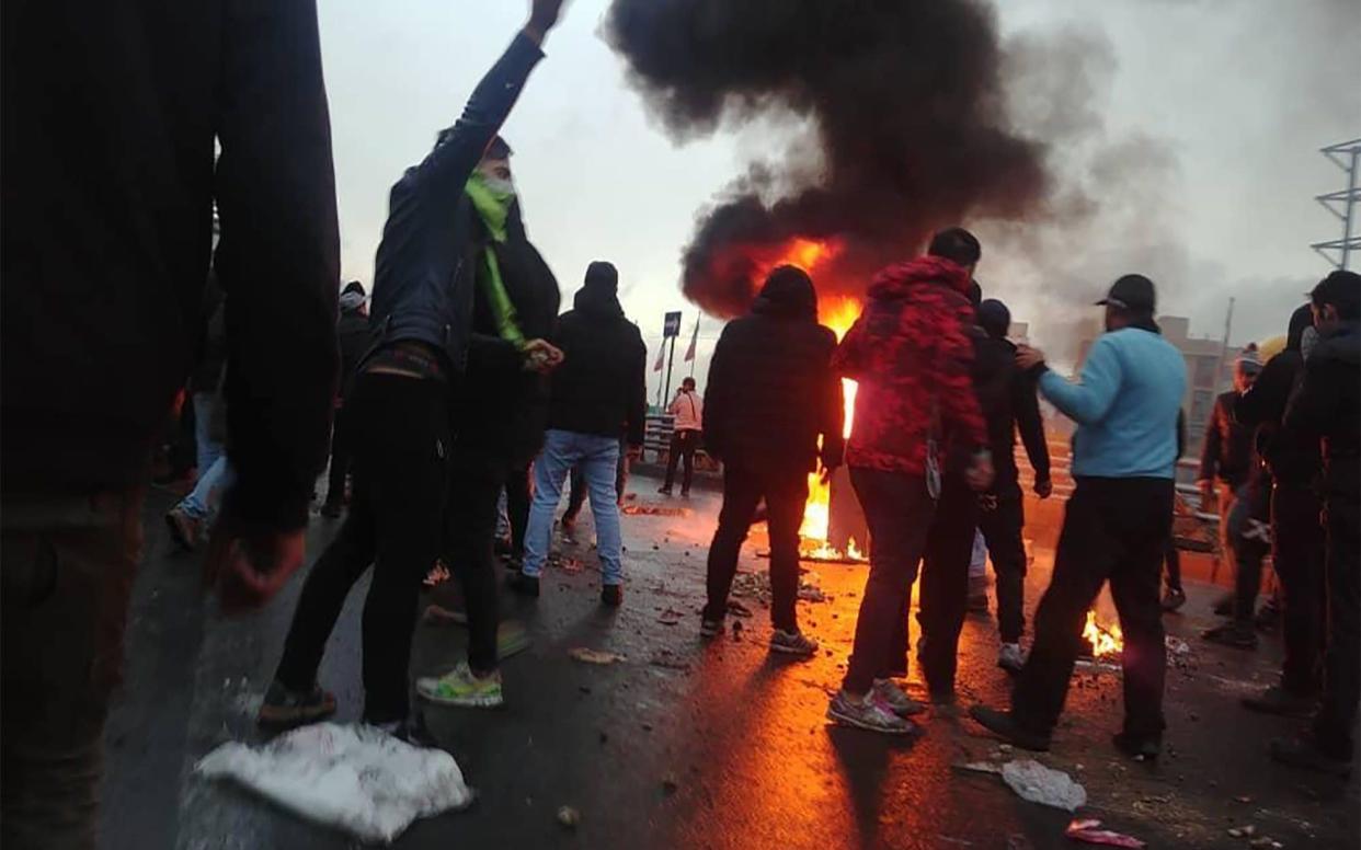 Iranian protesters gather around a fire during a demonstration against an increase in gasoline prices in the capital Tehran, on November 16, 2019 - AFP