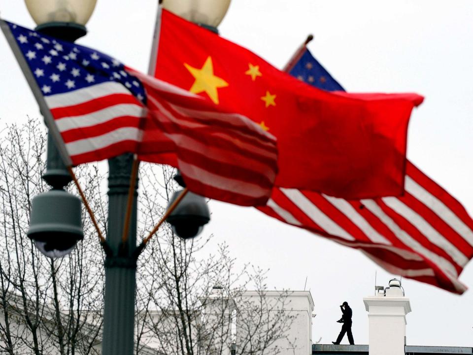 Aa Secret Service agent guards his post on the roof of the White House as a lamp post is adorned with Chinese and US national flags in Washington, DC: AFP via Getty Images