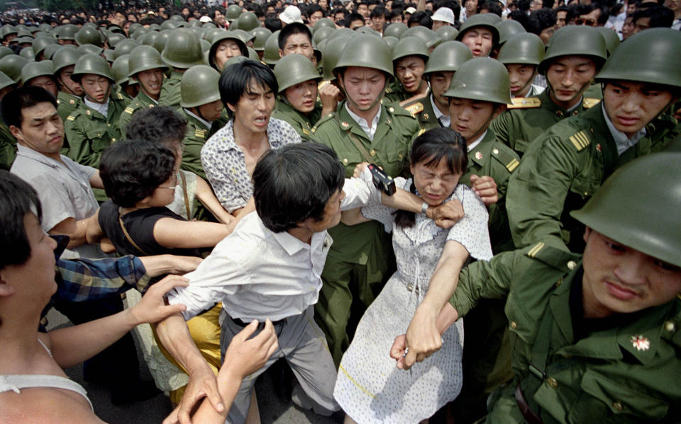 FILE - In this June 3, 1989 file photo, a young woman is caught between civilians and Chinese soldiers, who were trying to remove her from an assembly near the Great Hall of the People in Beijing. Over seven weeks in 1989, the student-led pro-democracy protests centered on Beijing’s Tiananmen Square became China’s greatest political upheaval since the end of the decade-long Cultural Revolution more than a decade earlier.(AP Photo/Jeff Widener, File)