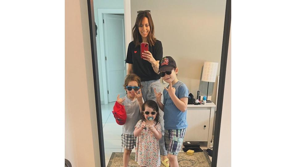 mother taking mirror selfie with three children 