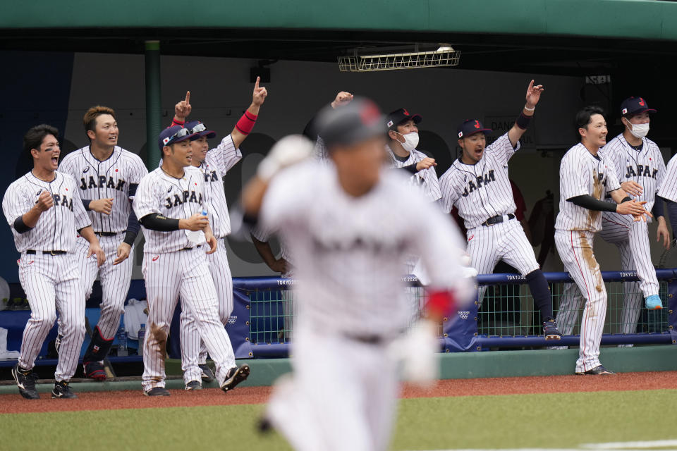 Japan players celebrate a walk-off single hit by Hayato Sakamoto, foreground, during the ninth inning of a baseball game against the Dominican Republic at the 2020 Summer Olympics, Wednesday, July 28, 2021, in Fukushima, Japan. Japan won 4-3. (AP Photo/Jae C. Hong)