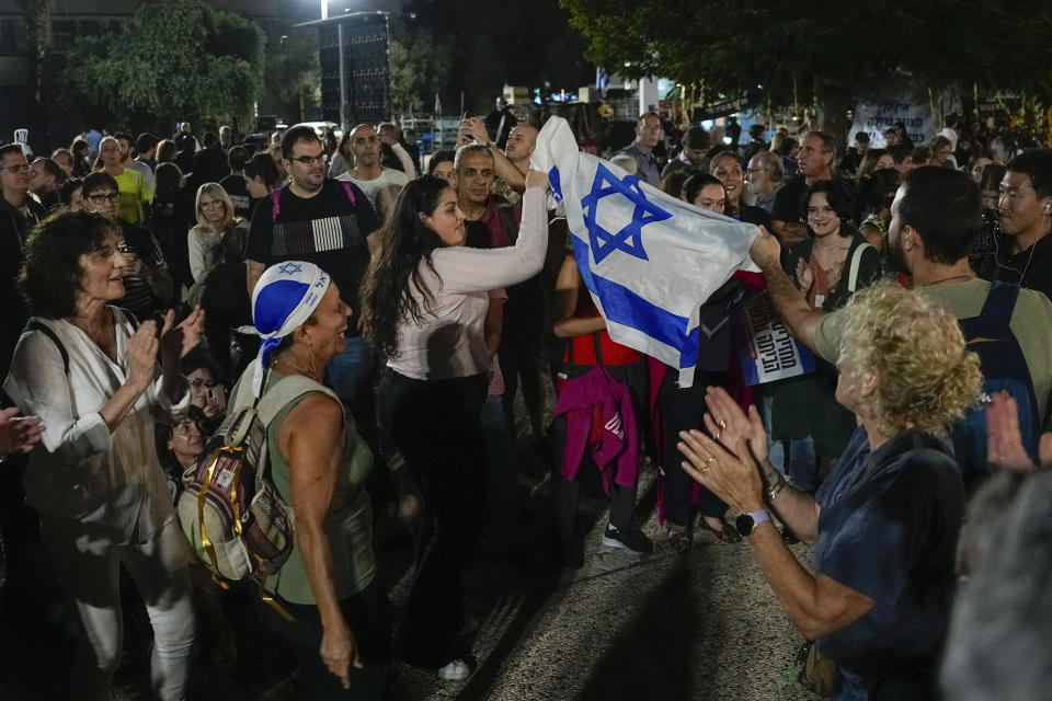 People react as they hear the news of the release of 13 Israeli hostages held by Hamas in the Gaza strip, in Tel Aviv, Israel, on Friday, Nov. 24, 2023. Friday marks the start of a four-day cease-fire in the Israel-Hamas war, during which the Gaza militants pledged to release 50 hostages in exchange for 150 Palestinians imprisoned by Israel. (AP Photo/Ariel Schalit)