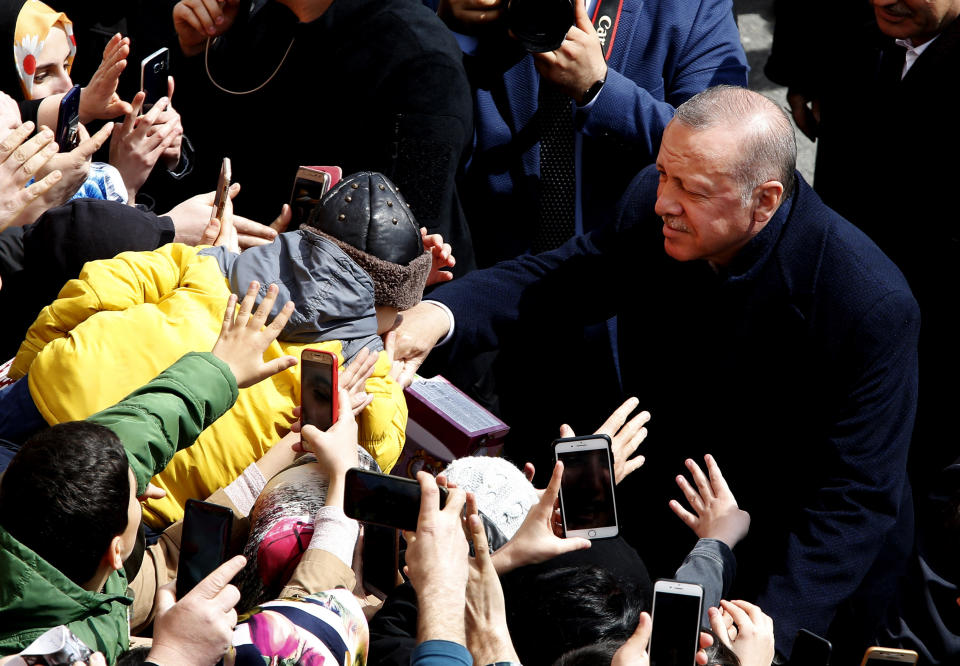 A boy kisses the hand of Turkey's President Recep Tayyip Erdogan outside of a polling station during local elections, in Istanbul, Sunday, March 31, 2019. Mayoral elections are underway in 30 large cities in Turkey along with other municipal races Sunday that are seen as a barometer of President Recep Tayyip Erdogan's popularity amid a sharp economic downturn in the nation straddling Europe and Asia. (AP Photo/Lefteris Pitarakis)