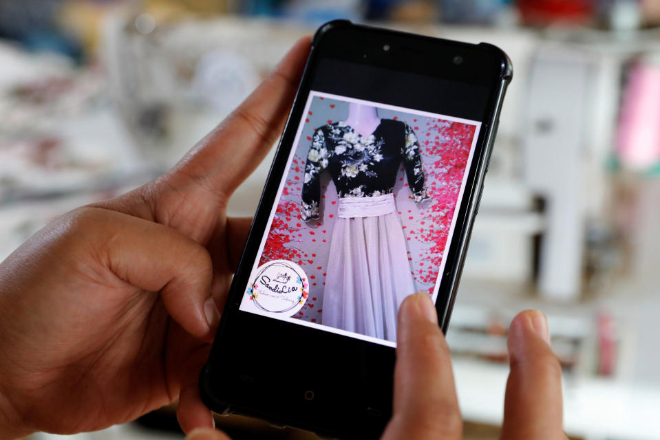 Asnia Muloc Sandiman, 25, shows a photo of a dress she made using a sewing machine provided by the government, in her family's tent at an evacuation camp in Marawi City, Lanao del Sur province, Philippines. (Photo: Eloisa Lopez/Reuters)