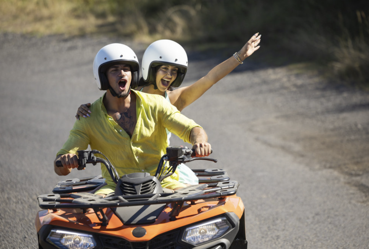 Leah Kateb and Miguel Harichi wear matching white helmets while riding an ATV.