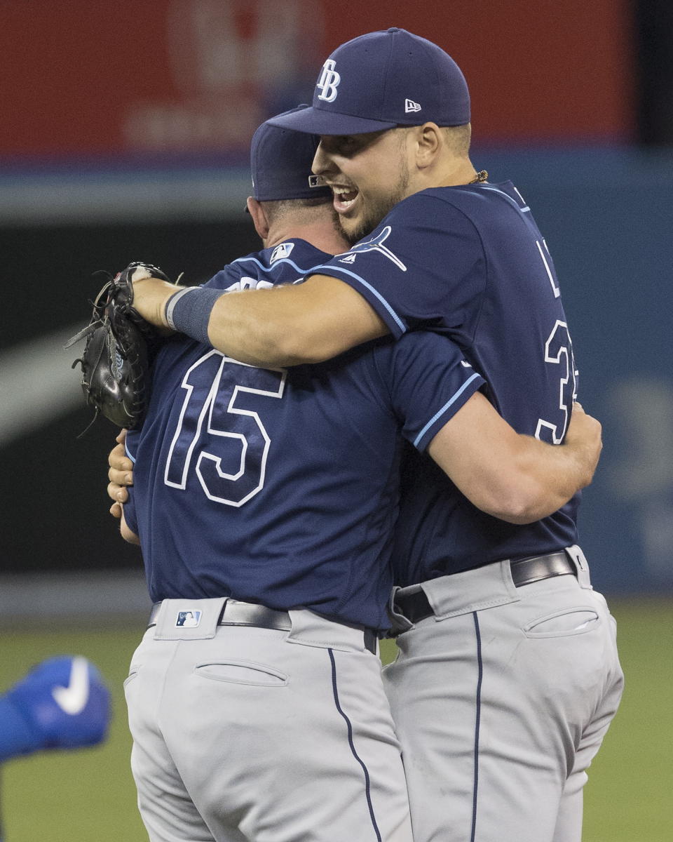 Tampa Bay Rays' Nate Lowe, right, and relief pitcher Emilio Pagan (15) celebrate on the field after they defeated the Toronto Blue Jays and clinched an American League wild-card berth in Toronto, Friday, Sept. 27, 2019. (Fred Thornhill/The Canadian Press via AP)