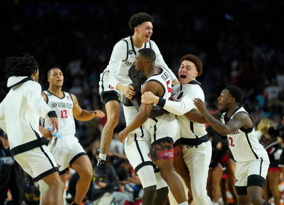 The San Diego State Aztecs mob Lamont Butler (5) after he hit a buzzer-beater to lift them into the national championship game.