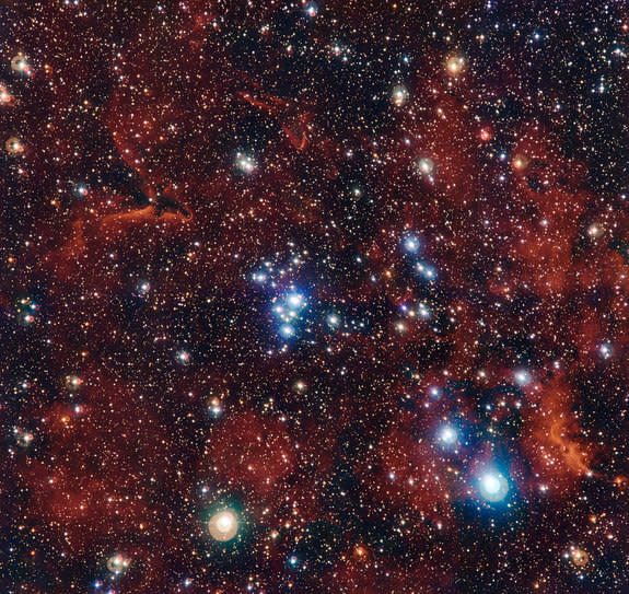 A cluster of young stars, glowing blue, travels through the red hydrogen gas of a nebula, embedded in an enormous supershell structure. This image of the cluster, NGC 2367, was taken by the MPG/ESO 2.2-meter telescope at the European Southern O