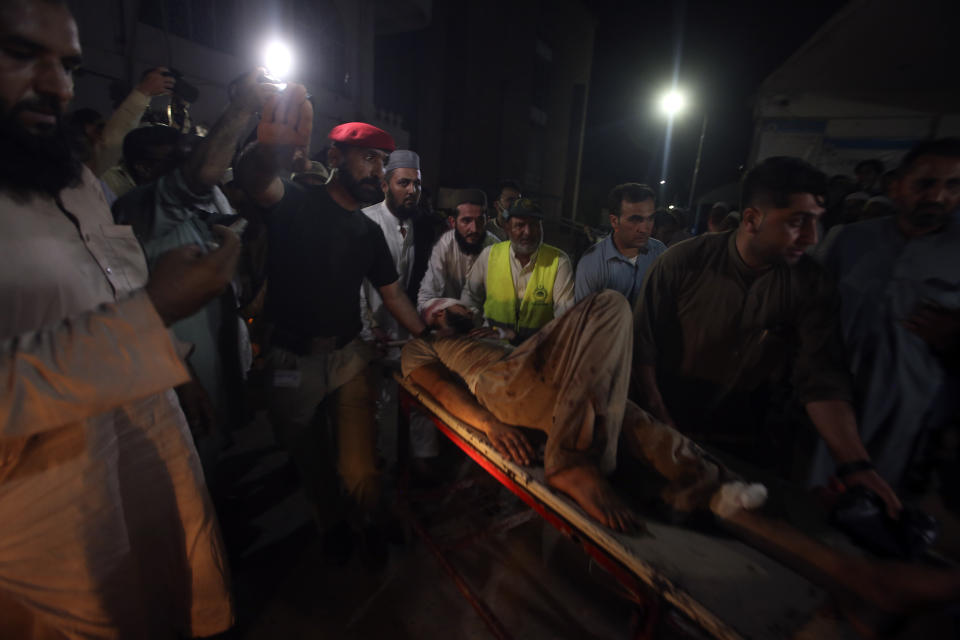 People transport an injured victim of a powerful bomb upon arrival at a hospital in Peshawar, Pakistan, Sunday, July 30, 2023. A bomb ripped through a rally by supporters of a hard-line cleric and political leader in the country's northwestern Bajur district that borders Afghanistan on Sunday, police and health officials said. (AP Photo/Muhammad Sajjad)