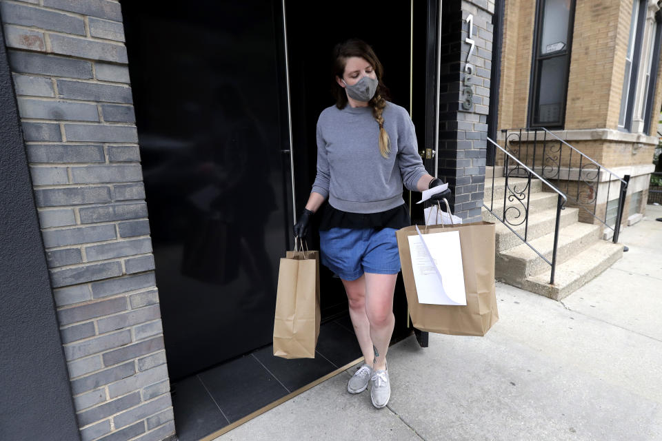 Marry Hammell, an Alinea restaurant staffer, carries out orders for a customer in Chicago, Saturday, June 20, 2020. Some of the world's best restaurants have had to make a quick pivot to weather the coronavirus. Alinea used to offer an 18-course tasting menu for $365; now it's making carryout meals for $49.94 (AP Photo/Nam Y. Huh)