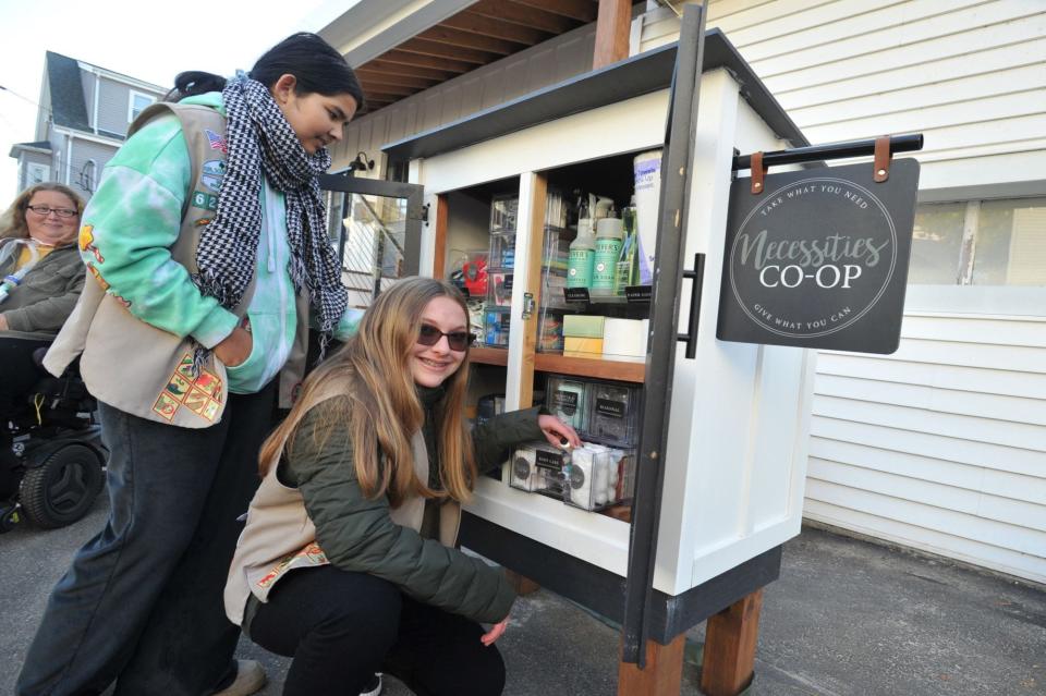 Braintree Girl Scout cadets Sophie Pradhan, 13, left, and Rileigh McLoughlin, 13, right, both of Braintree, stock donated personal care and household cleaning items in the Necessities Co-op pantry they created on Hall Avenue in South Braintree to help neighbors in need, Sunday, Nov. 12, 2023.