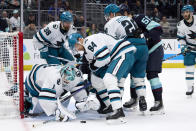 San Jose Sharks goaltender Devin Cooley (1) reaches for the puck with defenseman Jan Rutta (84) and defenseman Mario Ferraro (38) watching during the third period of the team's NHL hockey game against the Seattle Kraken, Thursday, April 11, 2024, in Seattle. (AP Photo/John Froschauer)