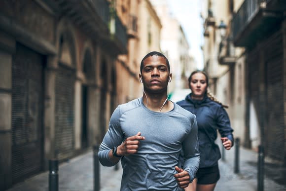 A man and a woman jogging while listening to music