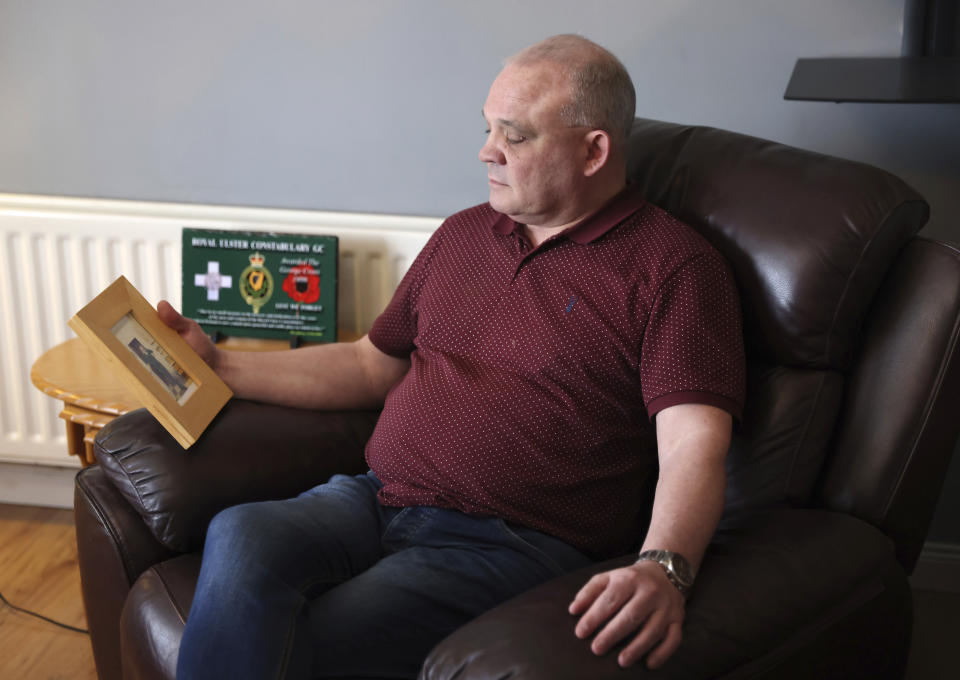 Peter Olphert, whose father, John, was shot dead by Irish Republican Army gunmen in 1983, looks at his father's photograph as he talks to The Associated Press from his family home in Limavady, Northern Ireland, Monday, April 3, 2023. As Northern Ireland marks 25 years since the Good Friday Agreement largely ended bloodshed that left 3,600 people dead, Olphert says it’s time to set aside the past and move on. (AP Photo/Peter Morrison)