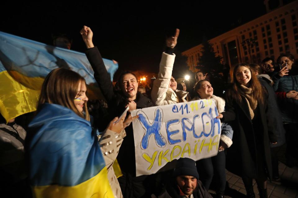 A crowd of cheering people holding signs and the Ukrainian flag