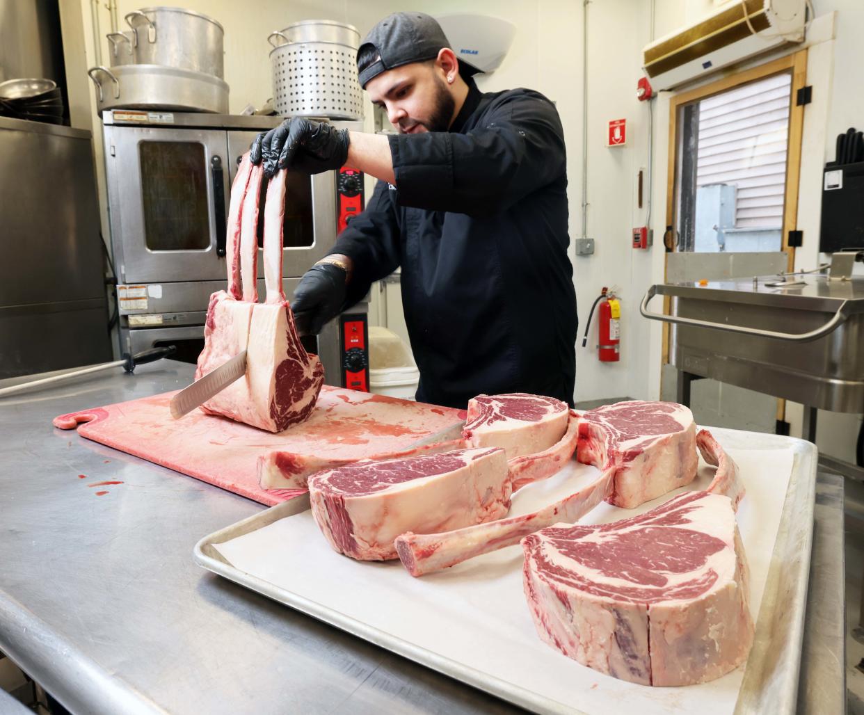 Manuel Hernandez, executive chef and co-owner of Barrels & Boards Restaurant and Marketplace in Raynham, slices a tomahawk ribeye steak on Wednesday, April 10, 2024.