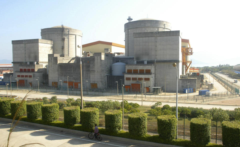 FILE - In this March 3, 2006 file photo, a Chinese cycles past the Daya Bay Nuclear Electricity Plant in Shenzhen, in China's southern Guangdong province. China is ready to approve new nuclear power plants as part of ambitious plans to reduce reliance on oil and coal, ending a moratorium it imposed because of Japan's Fukushima disaster in 2011. The Cabinet on Wednesday, Oct. 24, 2012, passed plans on nuclear power safety and development that said construction of nuclear power plants would resume "steadily." (AP Photo/Color China Photo, File) CHINA OUT