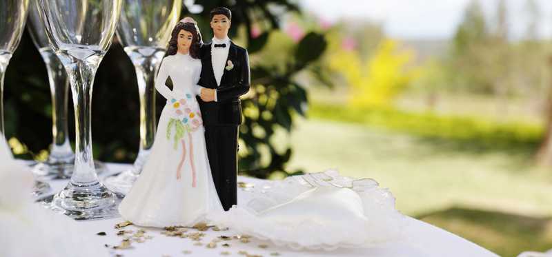 Bride and groom cake toppers sit on a table.