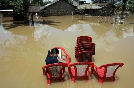A resident sits on a plastic chair in a flooded residential area in Jakarta in this March 15, 2007 file photo. REUTERS/Supri/Files